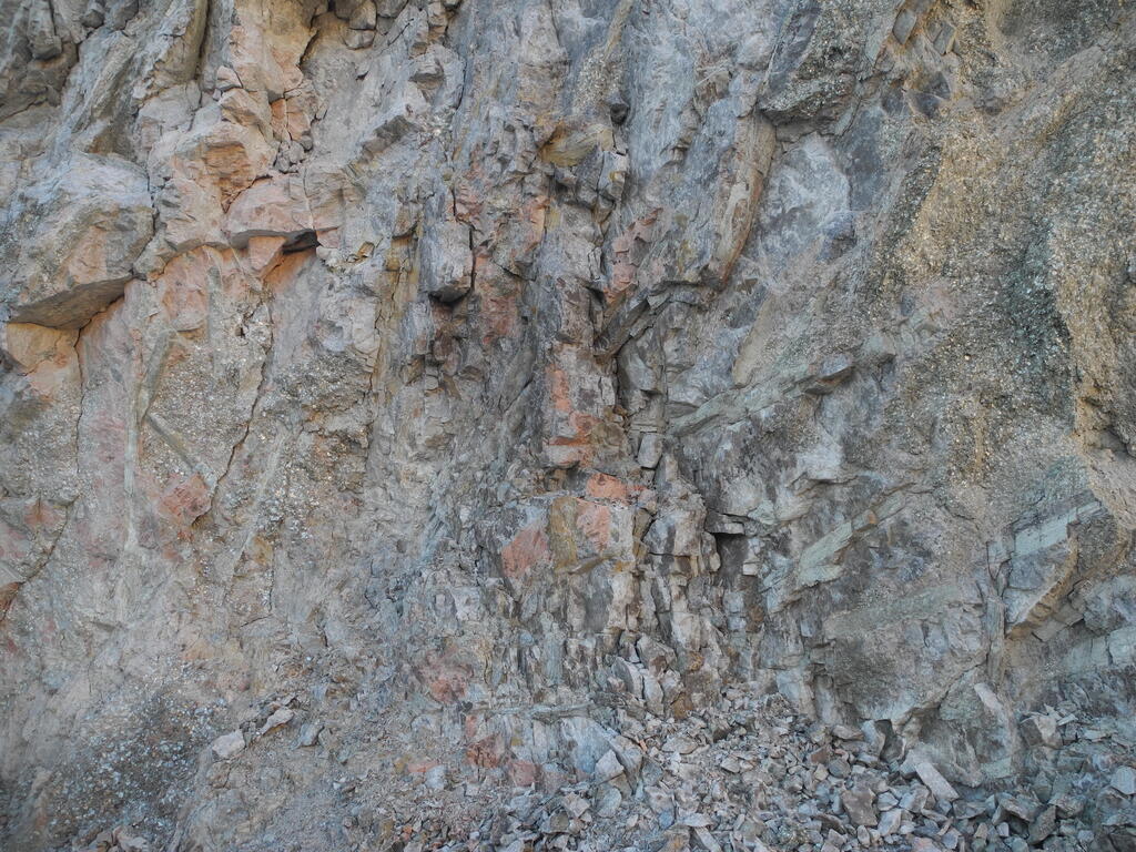 Große Spodumen Kristalle in der Wand des Steinbruchs und Bruchstücke davor